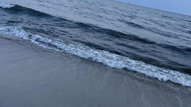 A beach with waves approaching the shore.