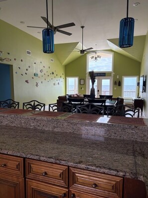 A kitchen with granite countertops, wooden cabinets, a dining area with chairs, and pendant lights.
