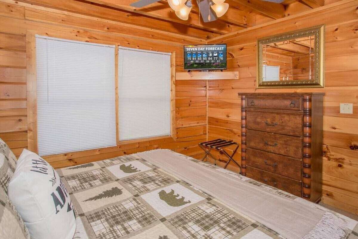 Een houten kamer met een bed, een dressoir, een spiegel en een bord met de weersvoorspelling voor zeven dagen.