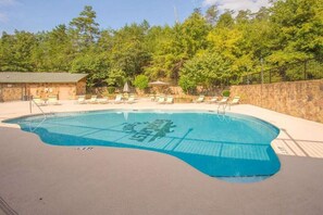 A swimming pool with lounge chairs and a stone wall.