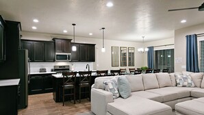 Une cuisine moderne avec des meubles de couleur sombre, un four à micro-ondes et un coin repas comprenant une table et des chaises.