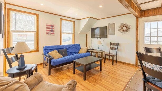 A living room with a blue sofa, a wooden coffee table, a TV mounted on the wall, and a fireplace. - Steps from the ocean in the heart of Hampton Beach! (Hampton)