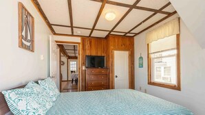 A bedroom with a bed, a dresser, a television, and a window. - Steps from the ocean in the heart of Hampton Beach! (Hampton)