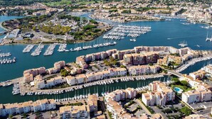 An aerial view of a marina with numerous boats docked, surrounded by residential buildings with balconies overlooking the water. - Beautiful apartment in villa for 6 people with WIFI, pool, A/C, terrace and pets allowed (Agde)