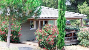 Une petite cabane avec un toit en tuiles, entourée de verdure et de plantes en fleurs.
