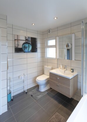 A modern bathroom with a toilet, sink, and mirror.