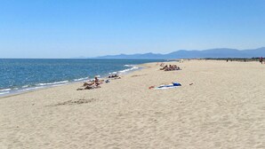 A wide sandy beach with a clear blue sky and distant mountains. - Lovely apartment in villa for 4 guests with WIFI, A/C, pool, TV, patio and pets allowed (Torreilles)
