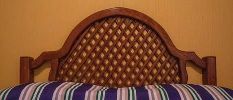 Una cama con cabecera de madera y colcha a rayas.