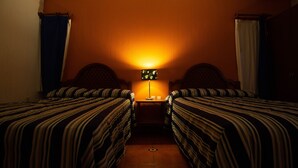 Una habitación de hotel con dos camas, una mesita de noche y una lámpara.
