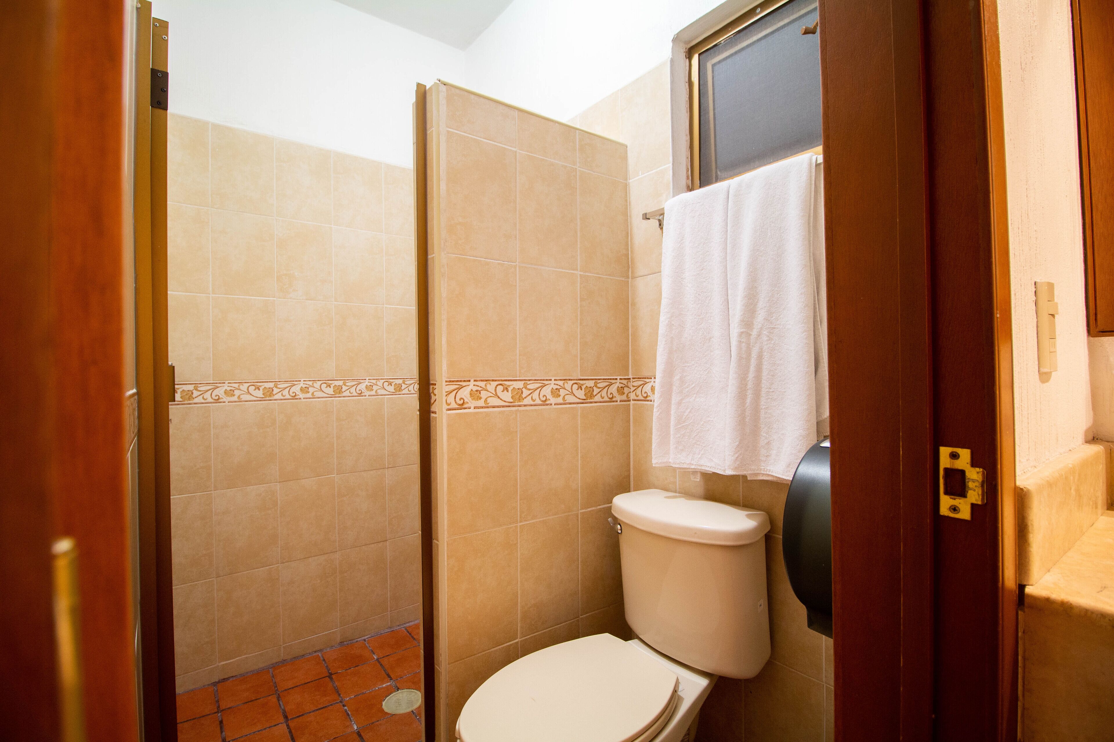 A bathroom with a shower, toilet, and a towel hanging on the wall.