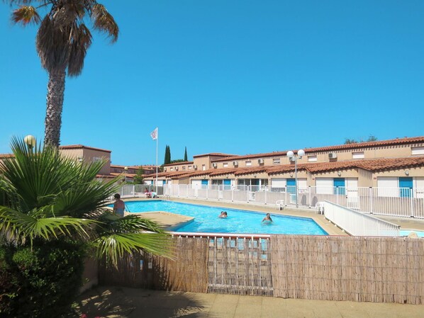 A pool area with multiple swimming pools, a palm tree, and a row of buildings with a tiled roof. - Beautiful apartment in villa for 6 guests with pool, TV, terrace and pets allowed (Saint-cyprien-plage)