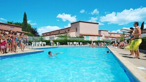 A swimming pool with people around it, a building with a tiled roof, and a clear blue sky. - Lovely apartment in villa for 6 guests with pool, A/C, TV, terrace and pets allowed (Saint-cyprien-plage)