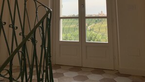 Una habitación con un ventanal grande, una escalera con barandilla metálica y techo de ladrillo.