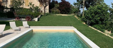 Una piscina al aire libre de temporada, sombrillas