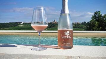 Una botella de vino Laffica y una copa sobre una mesa junto a la piscina, con vista a la piscina y al paisaje.