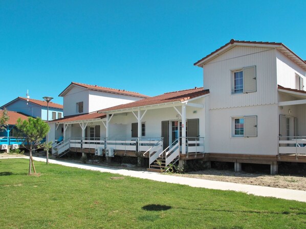 A two-story building with a covered porch and a staircase leading to the upper floor.