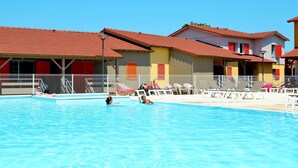 A swimming pool with lounge chairs and a building with red roofs and balconies. - Beautiful apartment in villa for 6 guests with pool, A/C, WIFI, terrace and pets allowed (Sète)