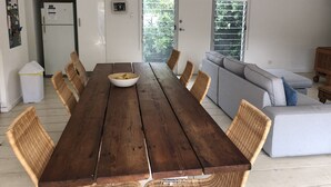A dining area with a wooden table, wicker chairs, and a grey sofa. - One of best locations at Coast. Surrounded by nature and the sound of surf. (Adelaide)