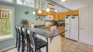 A kitchen with a central island, wooden cabinets, a microwave, a refrigerator, and a ceiling fan. - Blue Ridge Retreat w/ Deck: Hike, Sip & Explore! (Asheville)