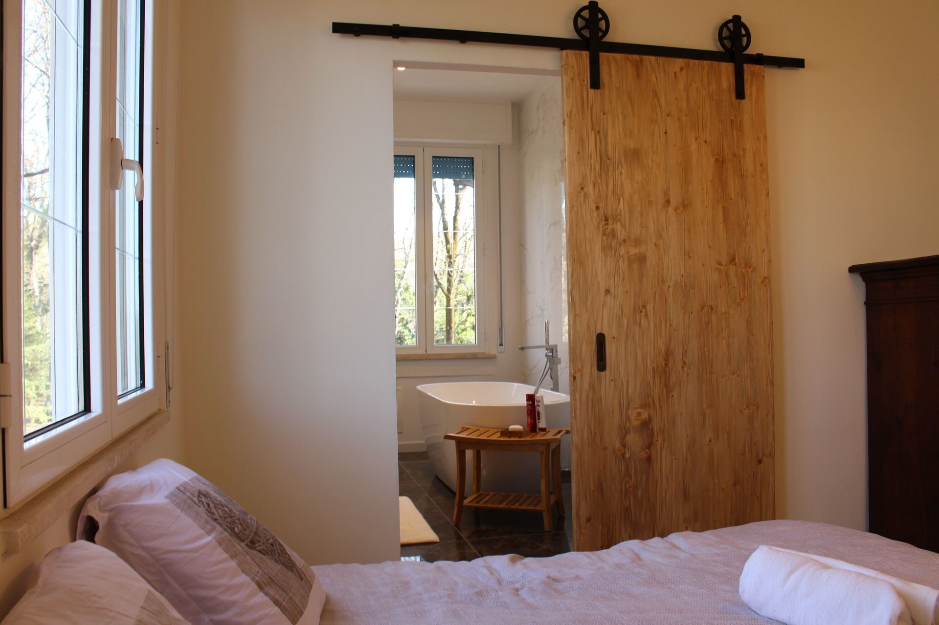 Ein Schlafzimmer mit einem Bett, einer Holztür, einem Fenster und Blick auf ein Badezimmer.