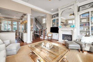 A spacious living room with a fireplace, a television, and a bookshelf. - Atlantus Cottage - steps to beach access (Saint Simons Island)