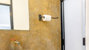 Un baño con un lavamanos color beige, inodoro y un bote de basura blanco.