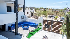 Un patio moderno al aire libre con una zona de estar azul, una piscina pequeña y vistas del vecindario circundante.
