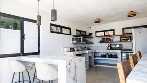 Una cocina moderna con una isla de mármol, taburetes de bar e iluminación colgante.