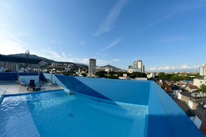 Une piscine sur le toit offrant une vue panoramique sur la ville, avec notamment une montagne et divers bâtiments.