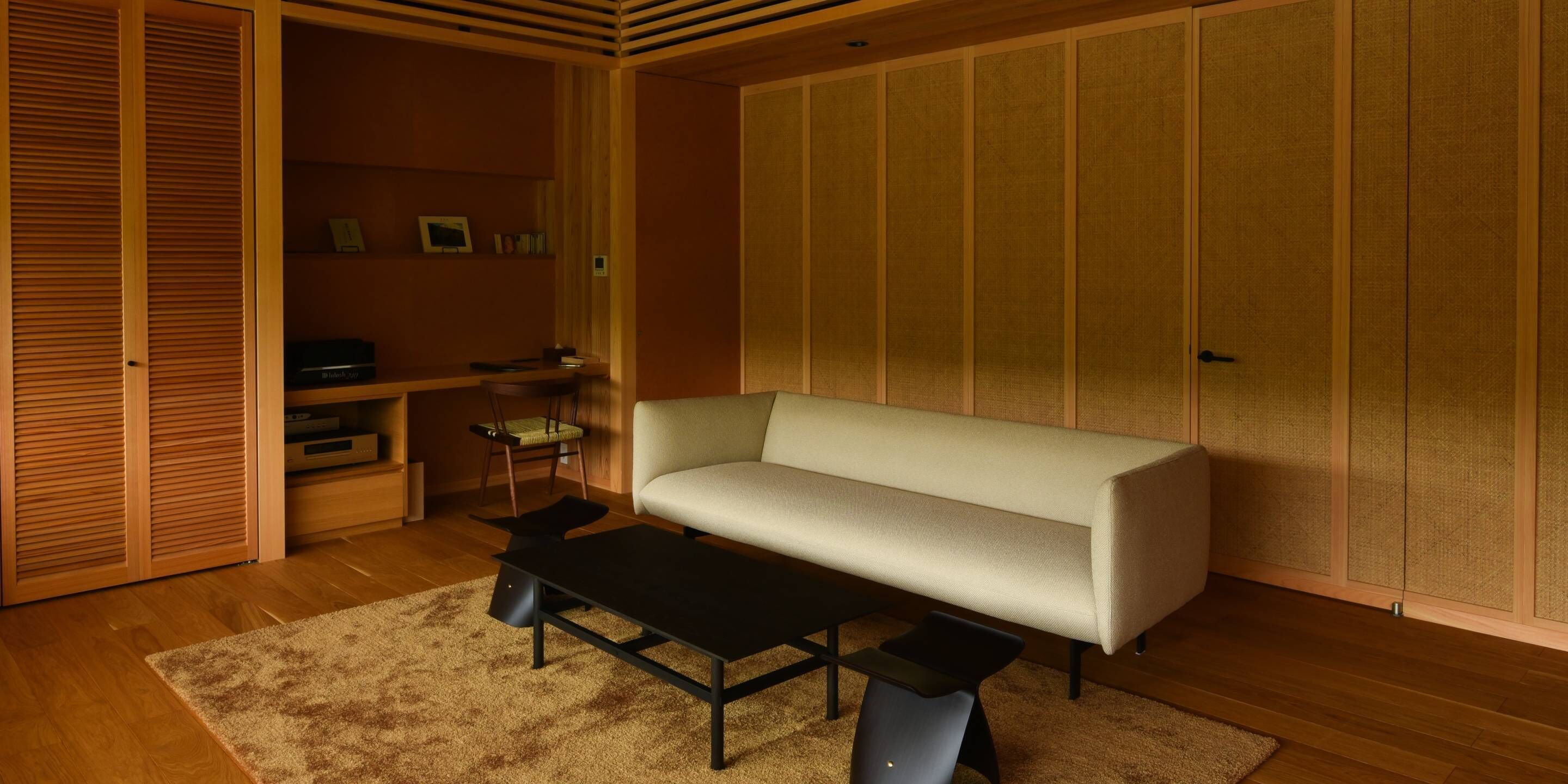 Ein Zimmer mit einer Couch, einem kleinen Tisch, einem Stuhl, einem Schrank und einer Schiebetür.