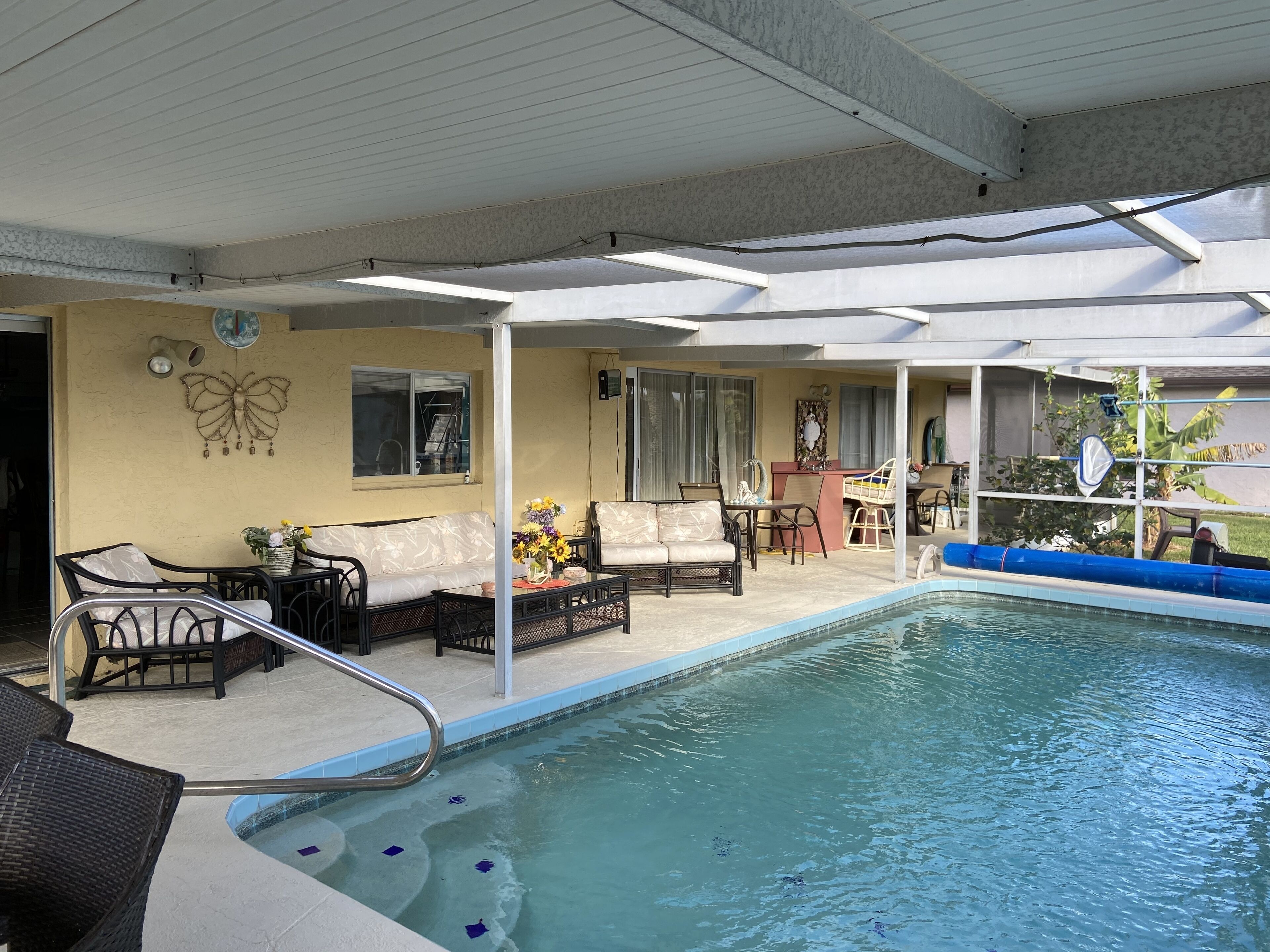 Un espace piscine aménagé avec des chaises longues, une table et un bar.