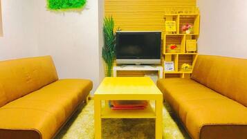 A living room with two sofas, a TV, a small table, and a shelf with items.