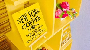 A yellow kiosk with a sign for New York Coffee, listing Latte, Cappuccino, and Caffe Mocha. - Local Tenjin House (Fukuoka)