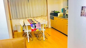 A compact living space with a dining table, a sofa, and a kitchen area. - Local Tenjin House (Fukuoka)
