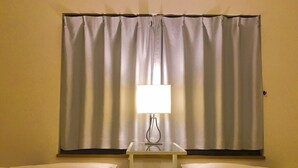 A hotel room with two beds, a nightstand with a lamp, and a window with curtains. - Local Tenjin House (Fukuoka)