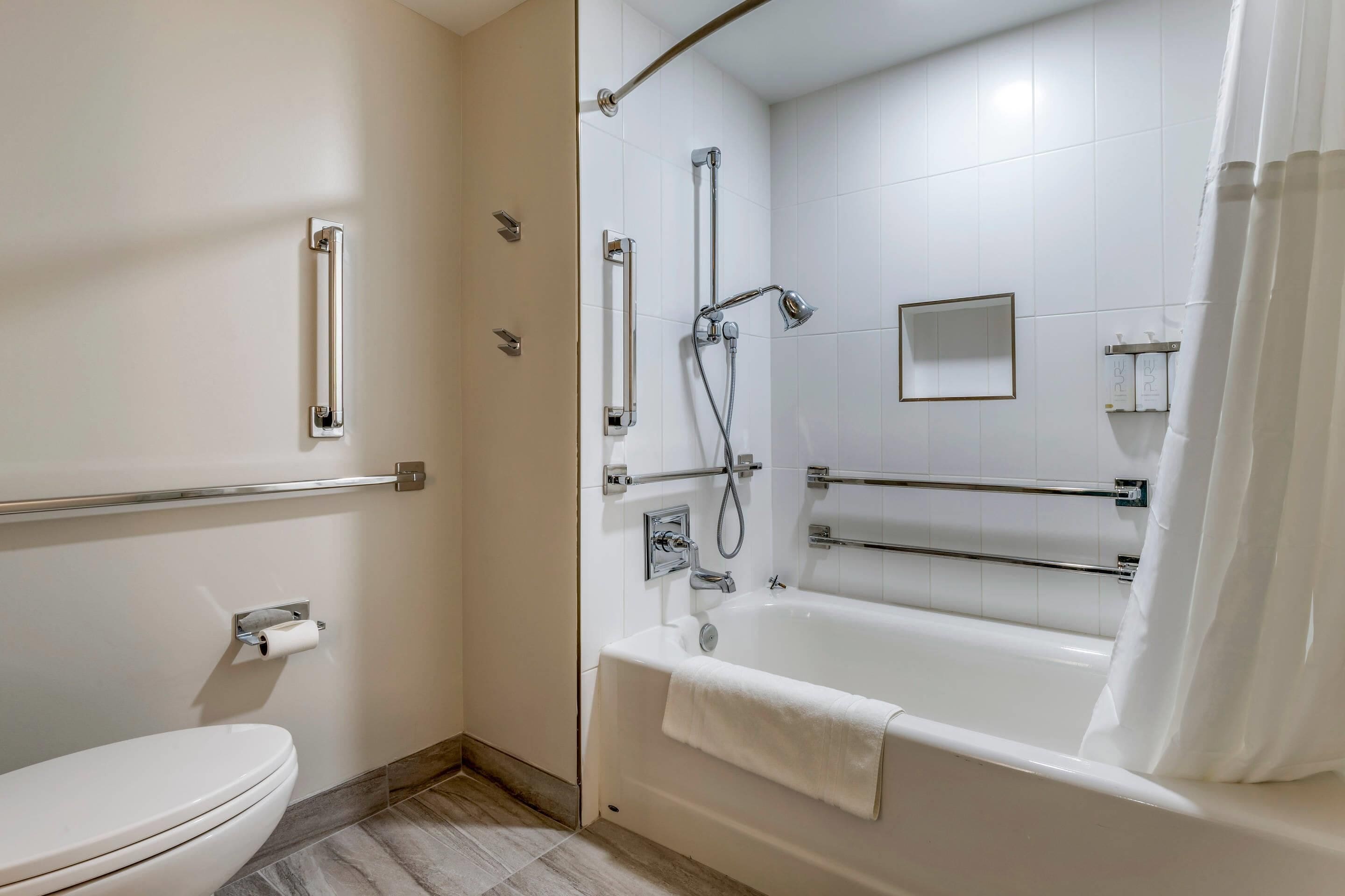 Un baño con inodoro, bañera, ducha y barandilla.