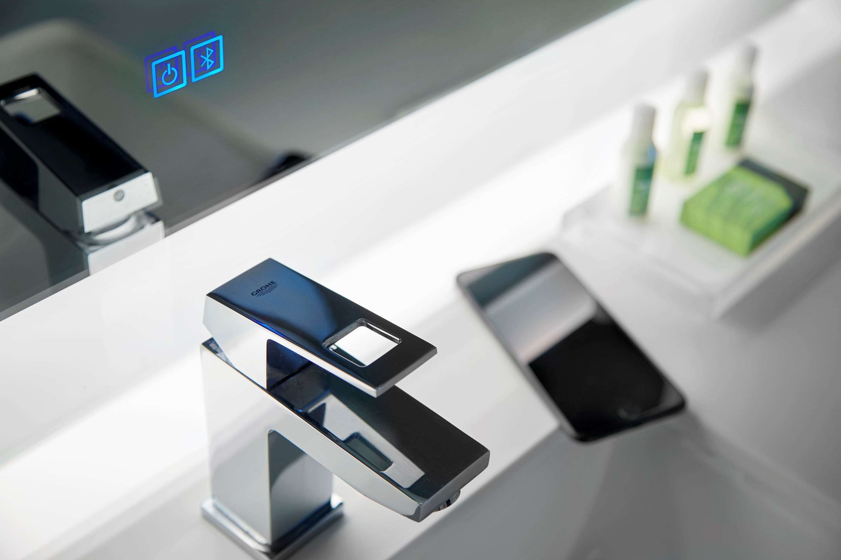 A modern, minimalist bathroom with a sleek, metallic faucet and a clear glass partition.