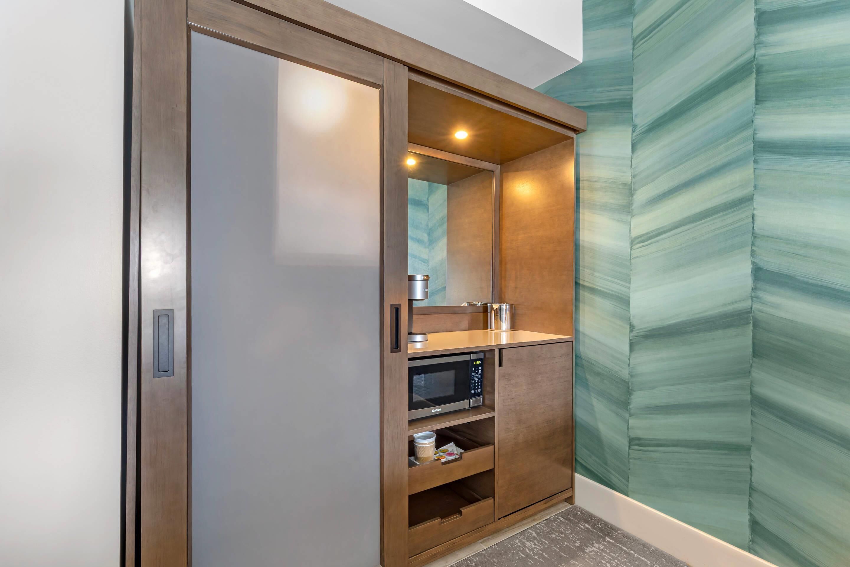 Un baño moderno con tocador de madera, microondas y espejo.
