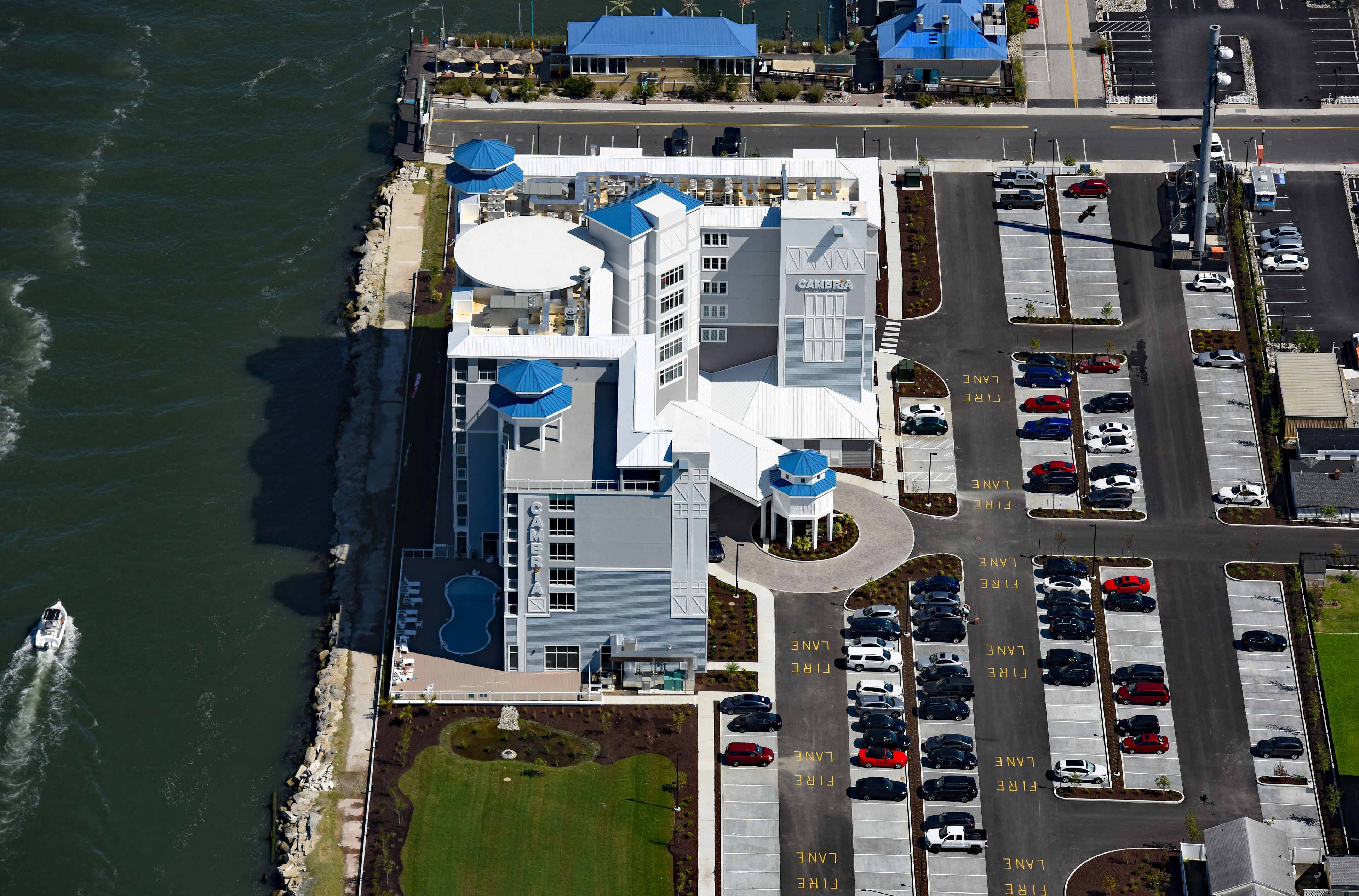 A coastal hotel with a parking lot and a view of the ocean.