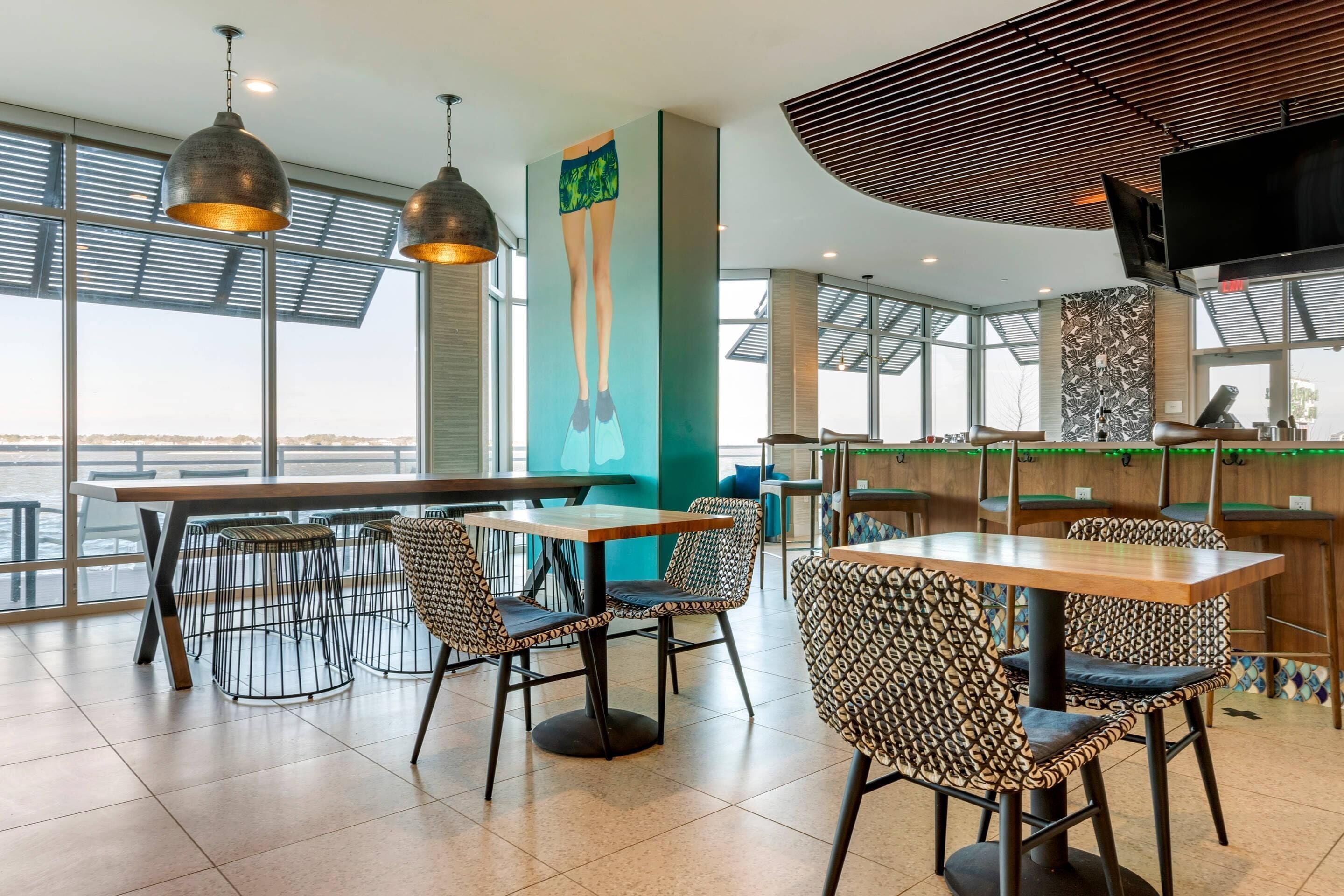 A modern restaurant with high ceilings, large windows, and a view of the city.