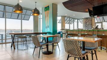 A modern restaurant with high ceilings, large windows, and a view of the city.
