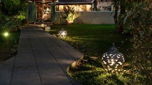 Un chemin bordé de guirlandes lumineuses menant à un bâtiment doté d’un balcon.