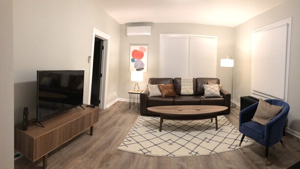 A living room with a TV, sofa, coffee table, and a blue armchair. - Fresh space near Mayo Clinic and downtown (Rochester)