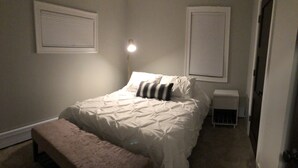 A bedroom with a bed, bedside table, bench, and wall-mounted lamp. - Fresh space near Mayo Clinic and downtown (Rochester)