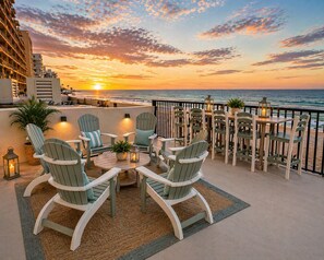A terrace with Adirondack chairs, a round table, and a view of the sunset over the ocean. - NEW Pool Open! Spectacular, Luxury, Direct Oceanfront, Balcony w/Gorgeous Views! (Daytona Beach Shores)