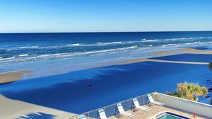 Ein Strand mit Poolbereich, einschließlich Liegestühlen und einer Person, die gerade geht.