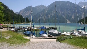 Un puerto deportivo con barcos amarrados, rodeado de montañas y un lago cristalino.