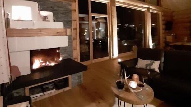 Una sala de estar acogedora con chimenea, un ventanal grande y un techo alto.