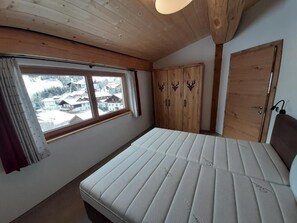 Un dormitorio con cama, ventana con cortinas, armario de madera y una puerta.