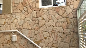 Un muro di pietra con una finestra e una ringhiera bianca.